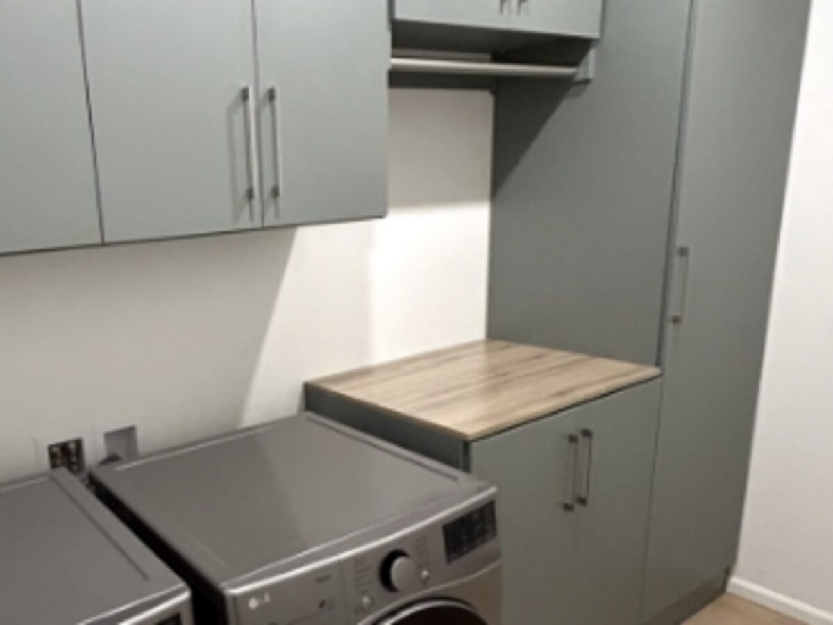 Custom laundry room cabinetry with folding counter over the washer